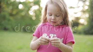可爱的小女孩带着小马尾巴在草地上摘花`花瓣。